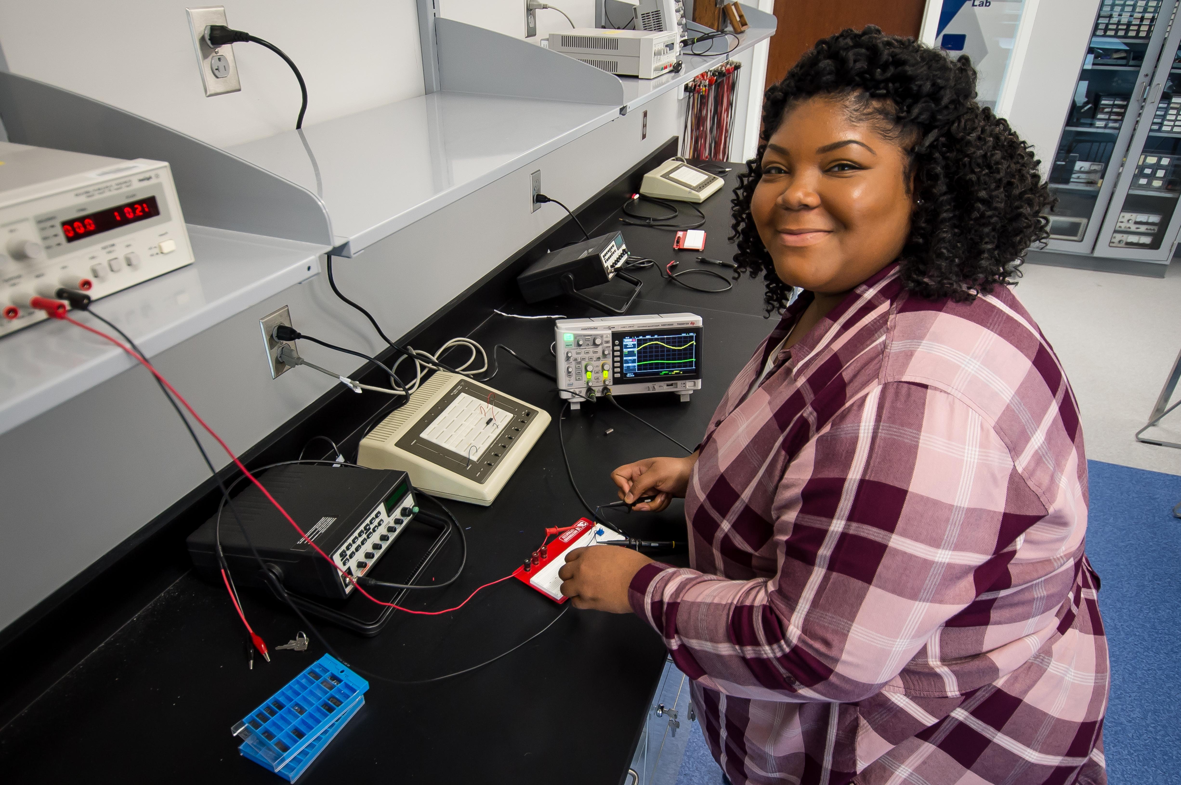 A female electrical engineering student soldering wires to a board