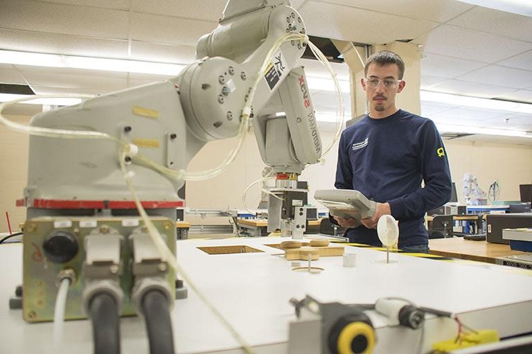 A student learns to train a robot using a teaching pendant